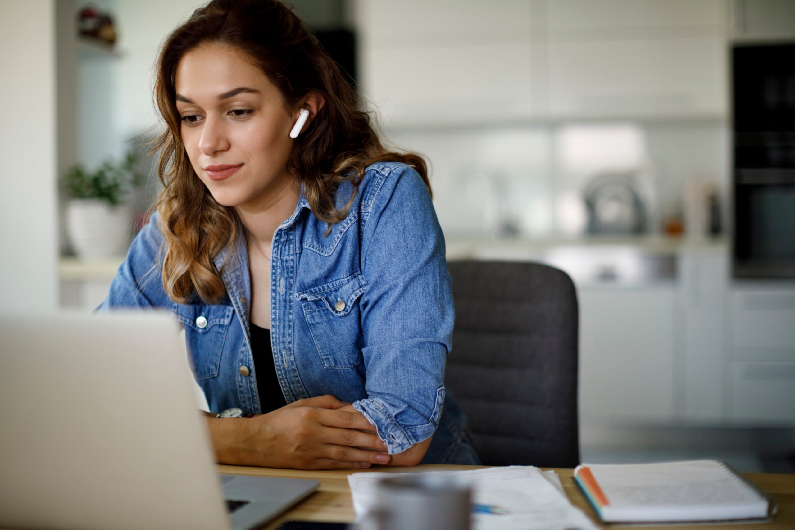 Woman with earphones looks at her laptop