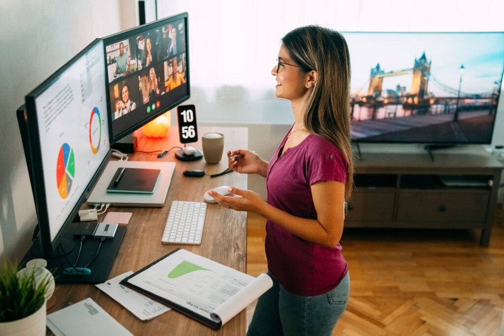 A woman smiles during a hybrid work meeting whilst working from home