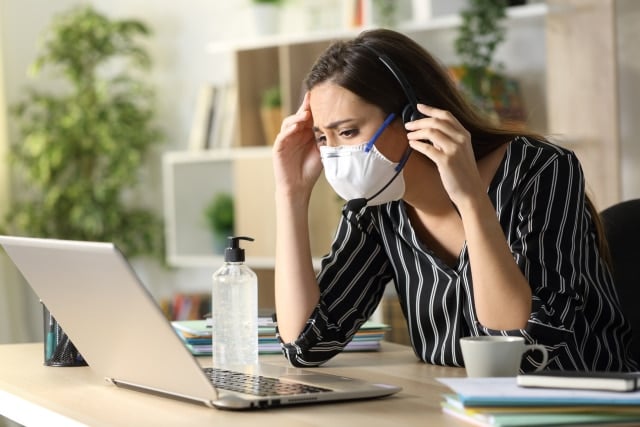 contact centre agent working from home wearing coronavirus mask having a difficult time at work