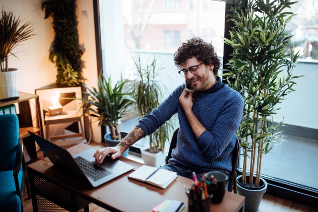 man using voice over IP VoIP to talk on the phone in his home office