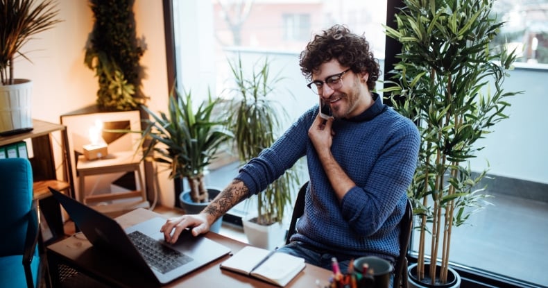 man using voice over IP VoIP to talk on the phone in his home office