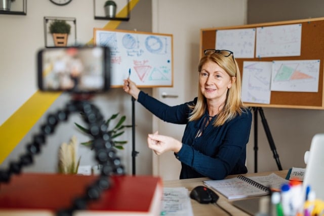 A teacher delivering a lesson using video conferencing from her living room