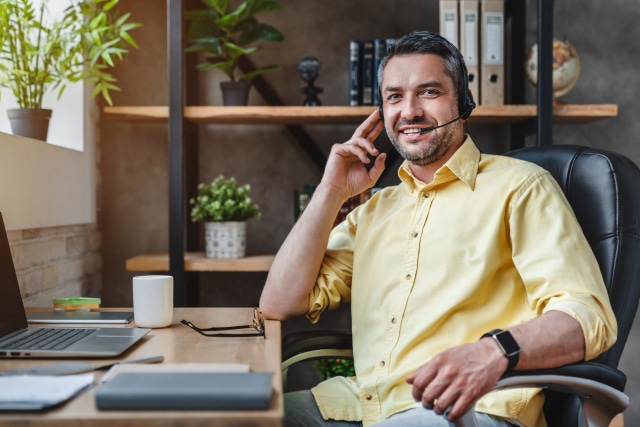 Male call centre agent wearing headset working from home