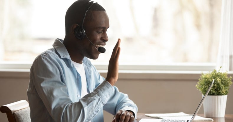 Man wearing headset starting video call greeting colleagues