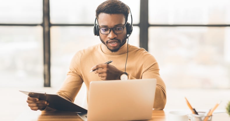 remote working male contact centre agent sat at a desk having a video call with a customer