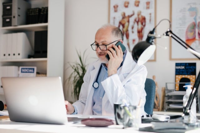 Doctor uses the phone in his office to confirm the test results for a patient-303