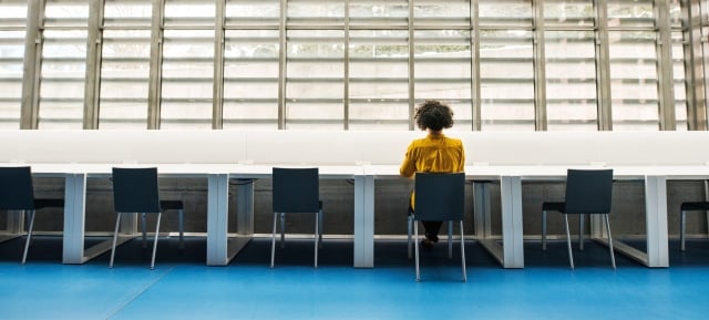 woman sitting at one chair in a row of chairs in an otherwise empty office