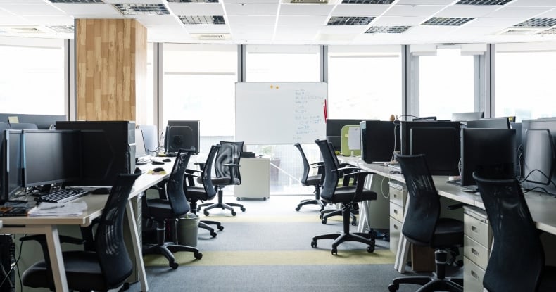 empty chairs and desktop pcs at desks in office