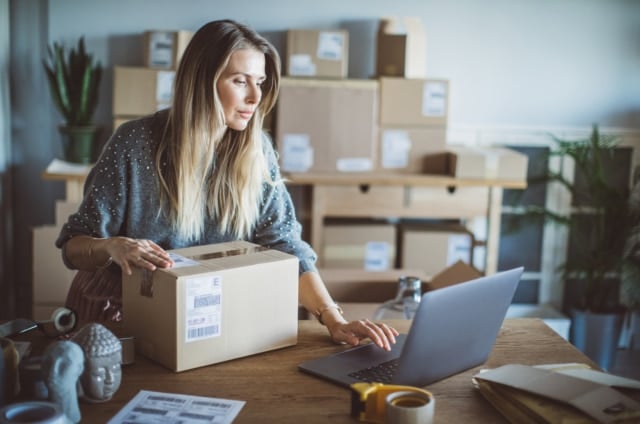 A businesswoman verifying a customer’s details while preparing to ship a product