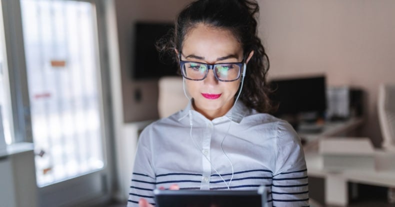 close up of beautiful caucasian woman with eyeglasses using tablet for video call earphones in ears