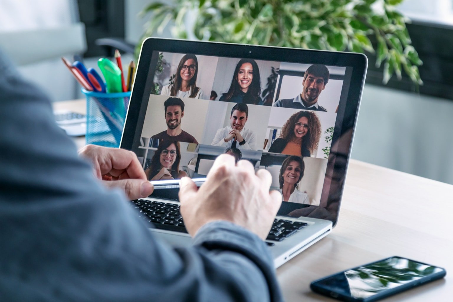 Male employee speaking on video call with diverse colleagues on online briefing with laptop at home.-750