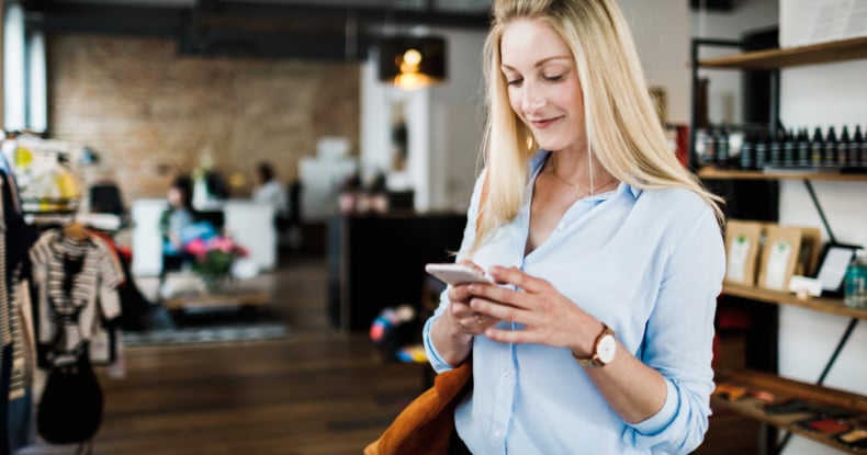 Woman Using SMS on Smartphone While Clothes Shopping