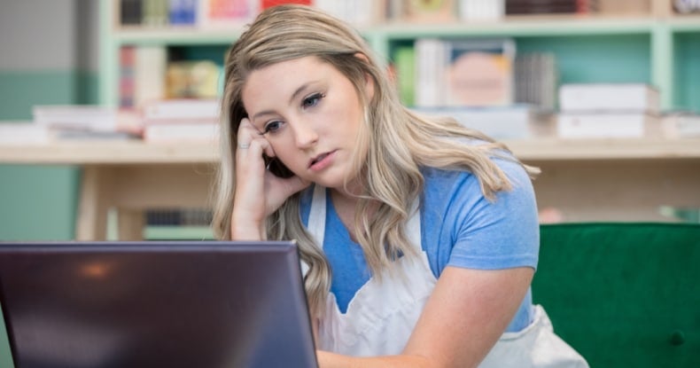 Frustrated small business owner looking frustrated while working on laptop in shop contacting customer service