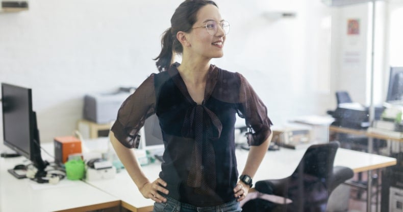 happy engaged and empowered female employee standing in the office