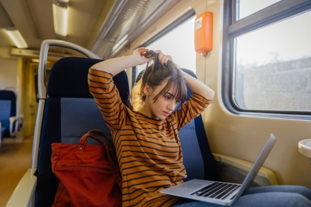 photo of woman working on a train with her laptop on her lap