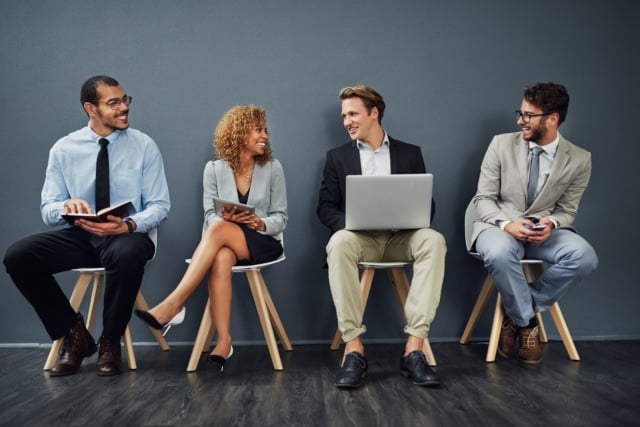 A group of working professionals sitting in chairs, smiling at eachother