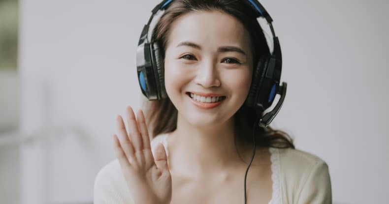 photo of a woman wearing headphones smiling and waving as if on a video conferencing call