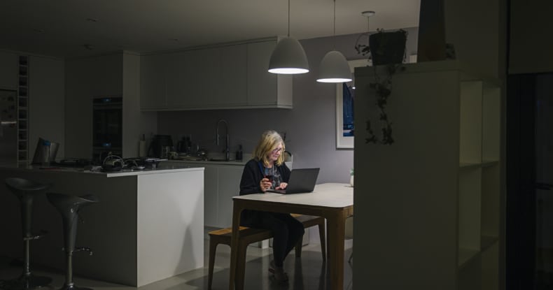 woman working at her kitchen table at night on her laptop