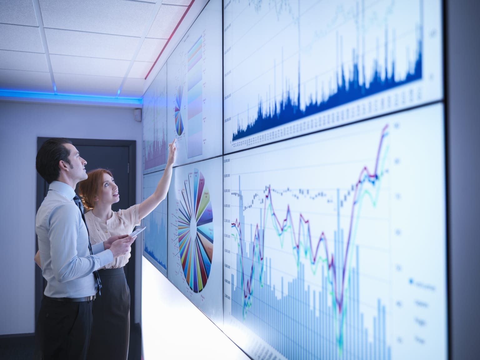 Business colleagues studying graphs on screen in meeting room-855