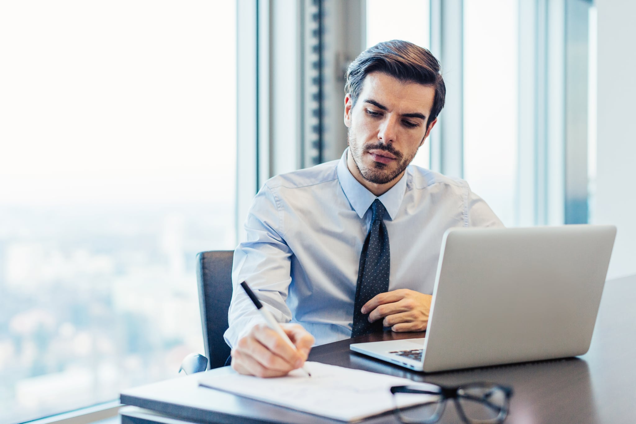 Businessman sitting in his office, writting on papers