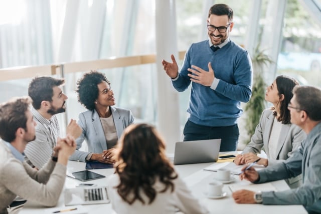 Happy businessman leading the meeting in the office while talking to his colleagues.