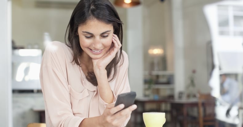 Smiling businesswoman looking down at cell phone in cafe window-488