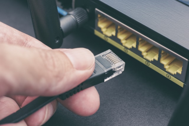 a man plugging in cable to wireless router