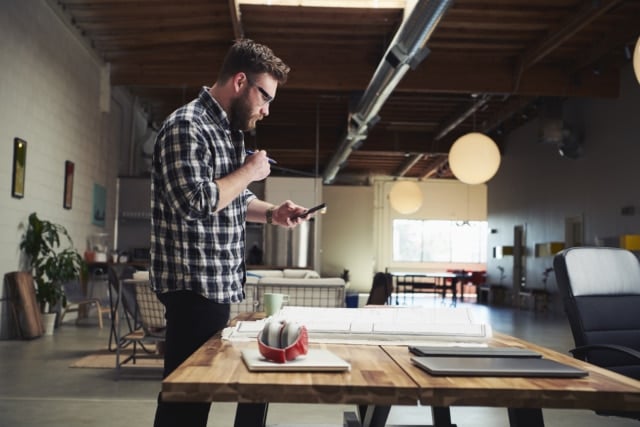 Architect standing at desk looking at mobile phone-936