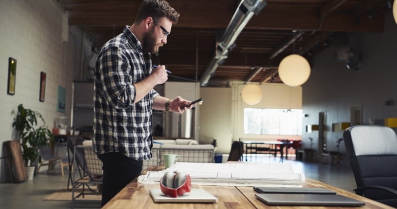 Architect standing at desk looking at mobile phone-936