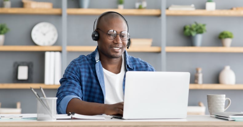 Hotline support service. African american male call center operator in headset working with laptop computer at home