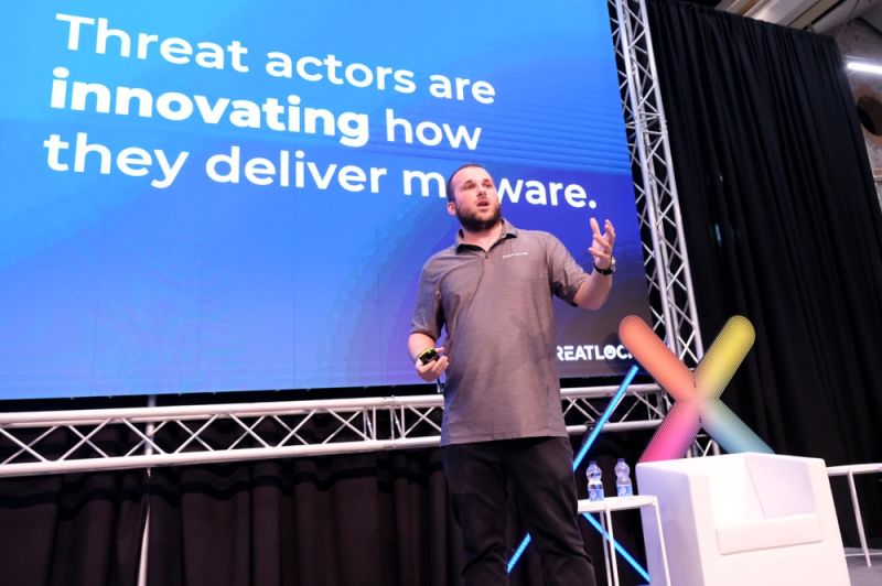 A man standing on stage in front of a screen