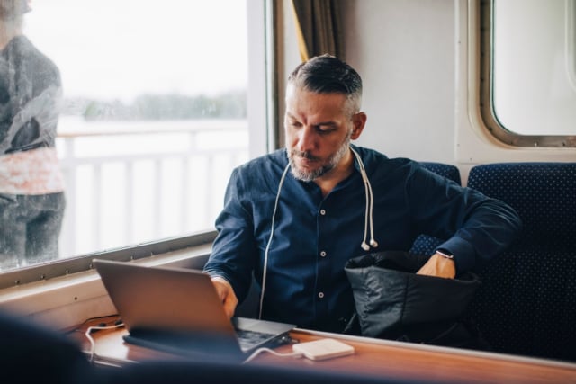 Confident male entrepreneur using laptop by window while traveling in ferry-344