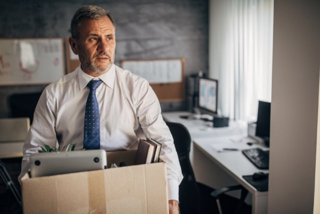 A senior man carrying a box of possessions after retiring