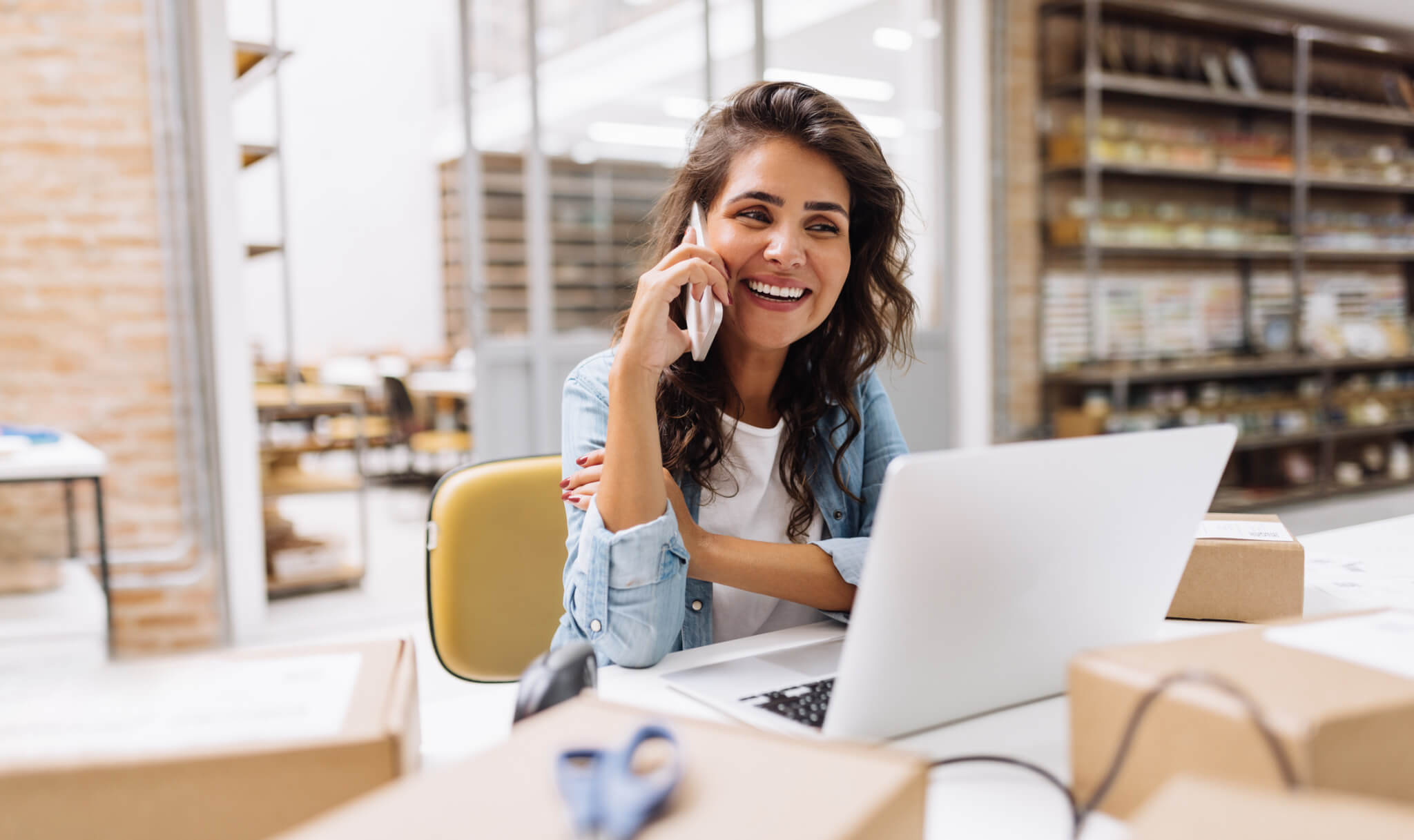 Happy young businesswoman speaking on the phone in a warehouse-713