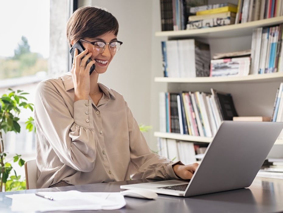 Young business woman using laptop and talking on cellphone