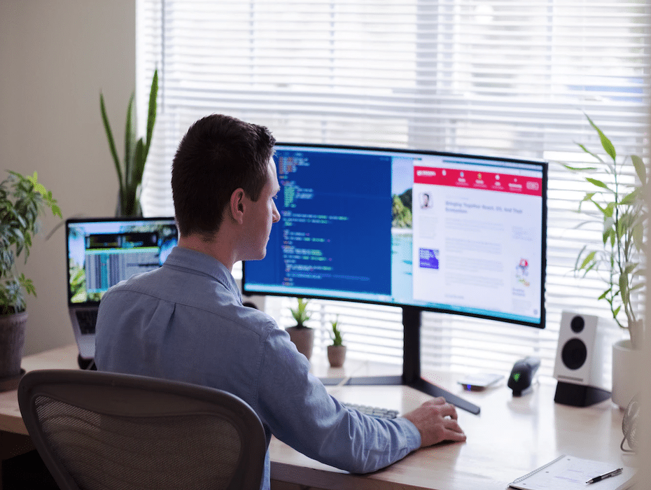 Man working from home with laptop and two monitors