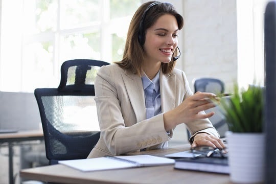 Beautiful smiling call center worker in headphones is working at modern office.