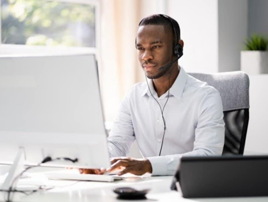 Business Service Agent With Headset At Computer On Phone