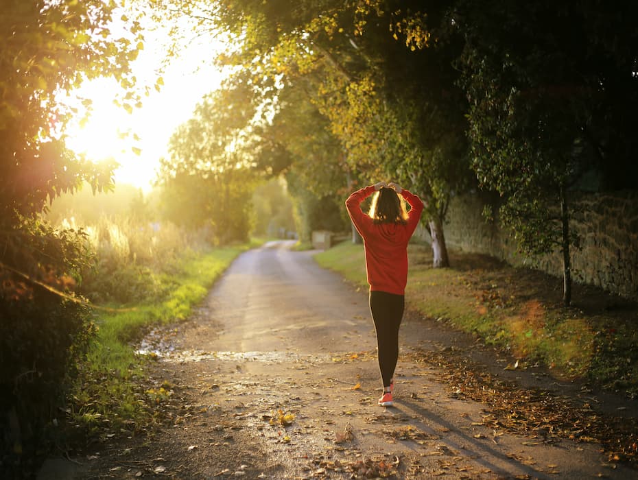 Woman walking down dirt path at sunrise