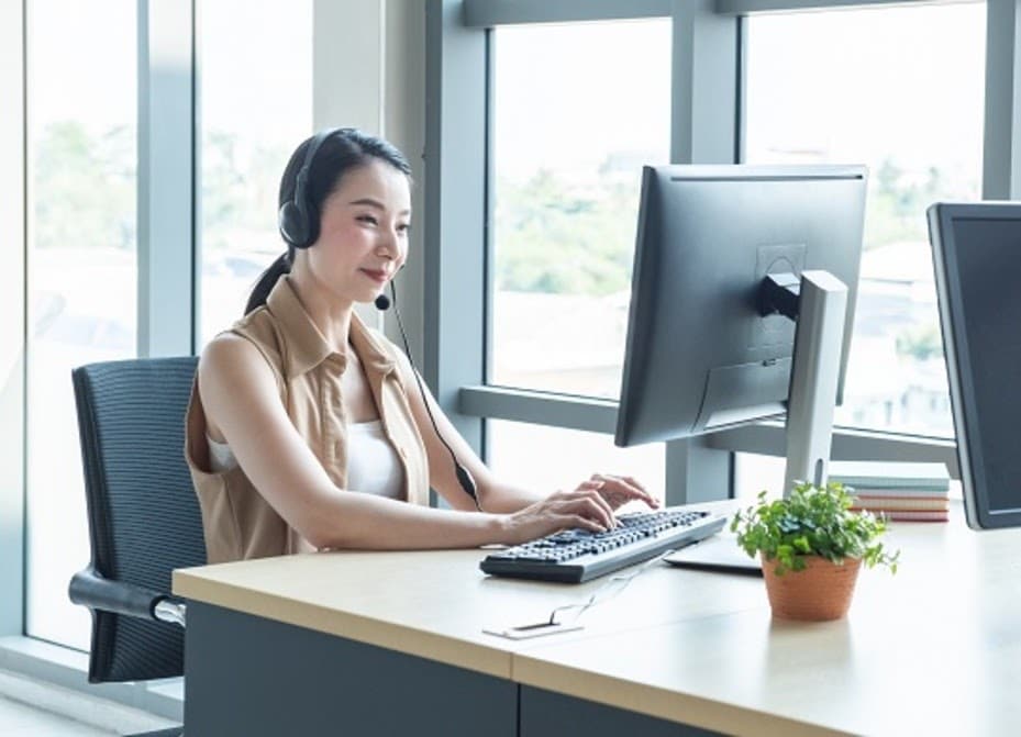 Smiling woman typing on a computer keyboard