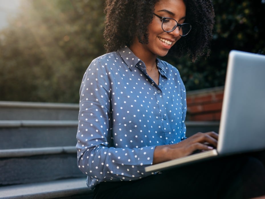 Businesswoman sitting on steps outdoors working on laptop