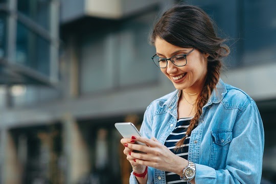 Young woman reading a message on the phone in the city