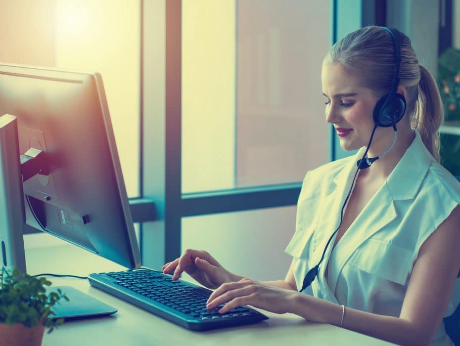 Happy Caucasian business woman using computer and headphone for