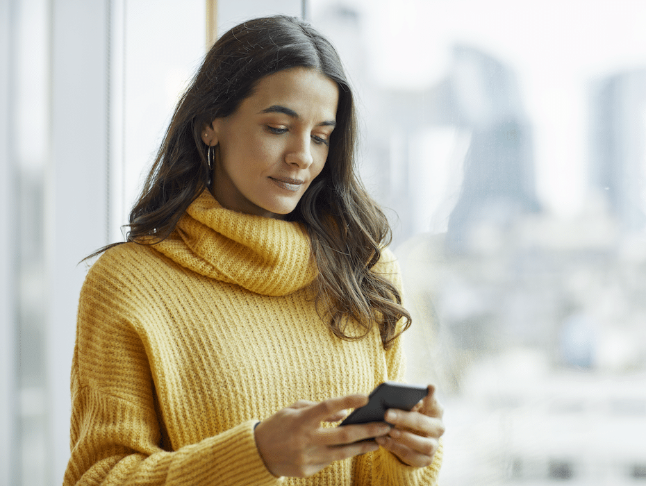 Confident businesswoman using mobile phone for business SMS messages.