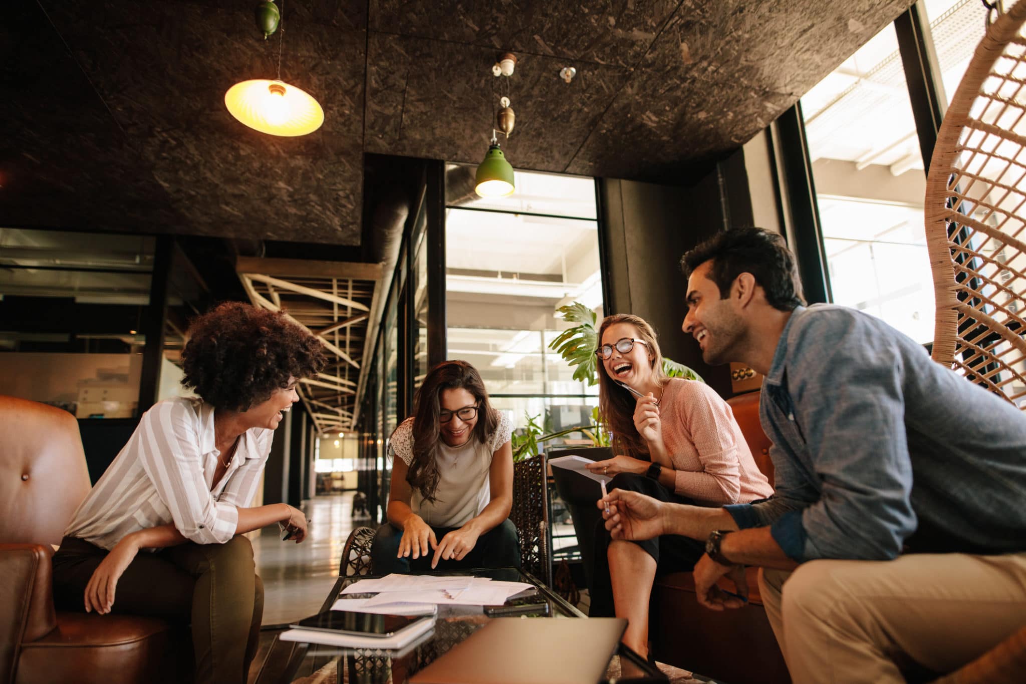 Diverse group of young workers sitting in a circle socializing and laughing