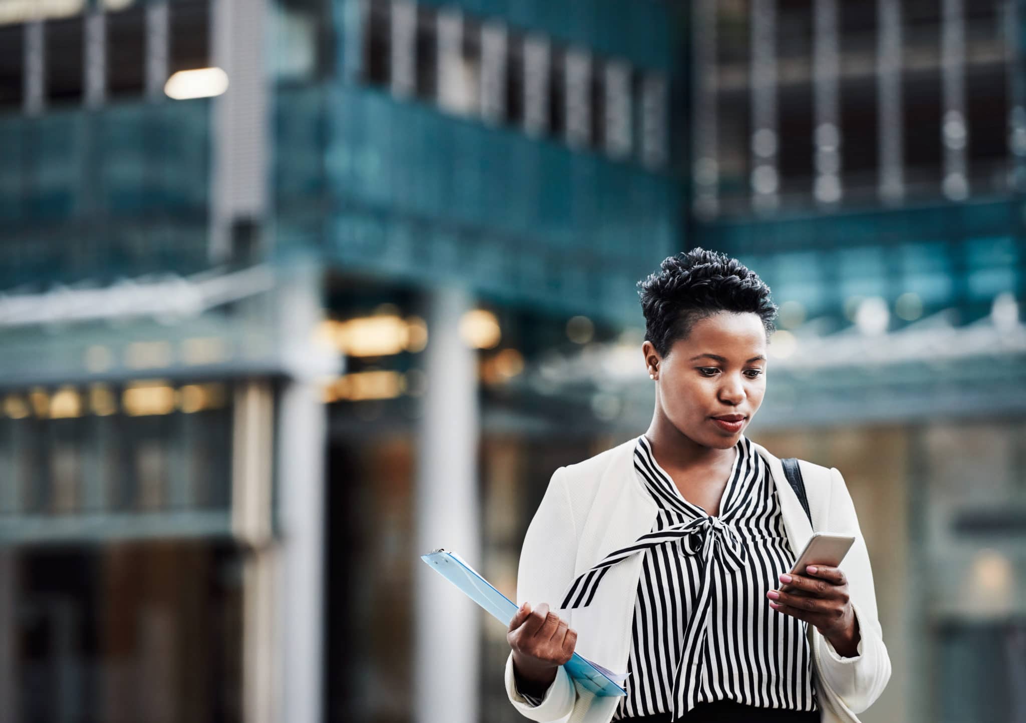 Shot of a young businesswoman using a mobile phone on the go in the city