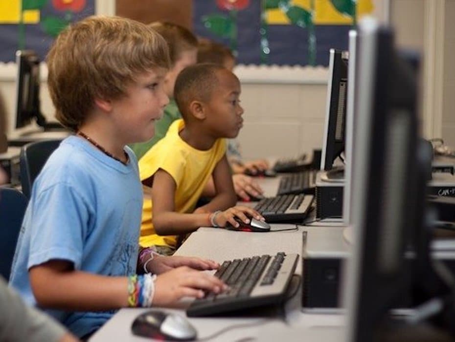 Students sitting side-by-side at computers and leveraging AI technologies to learn digitally.