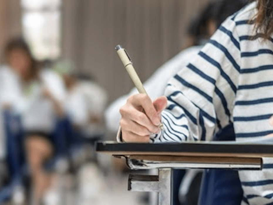 Close-up of a student learning with blurred view of students in background. Classroom setting. Personalized learning focus.