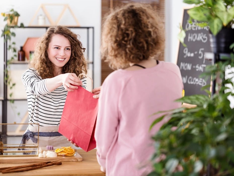 A retail associate gives a consumer items she purchased online and is picking up in store