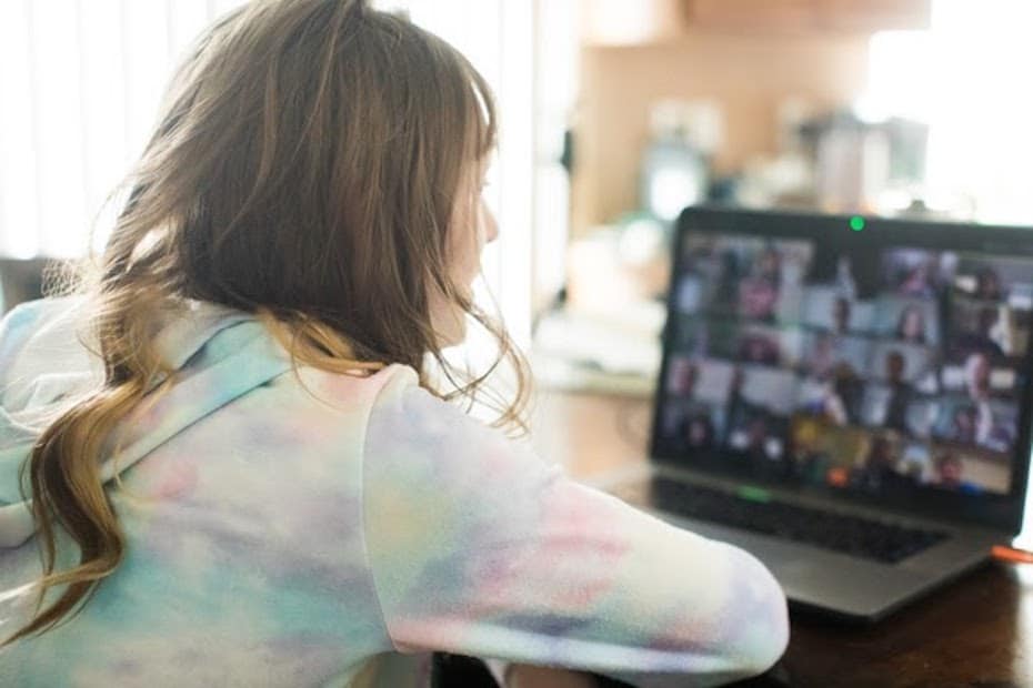 Female student learning remotely on her laptop while attending an online video meeting.